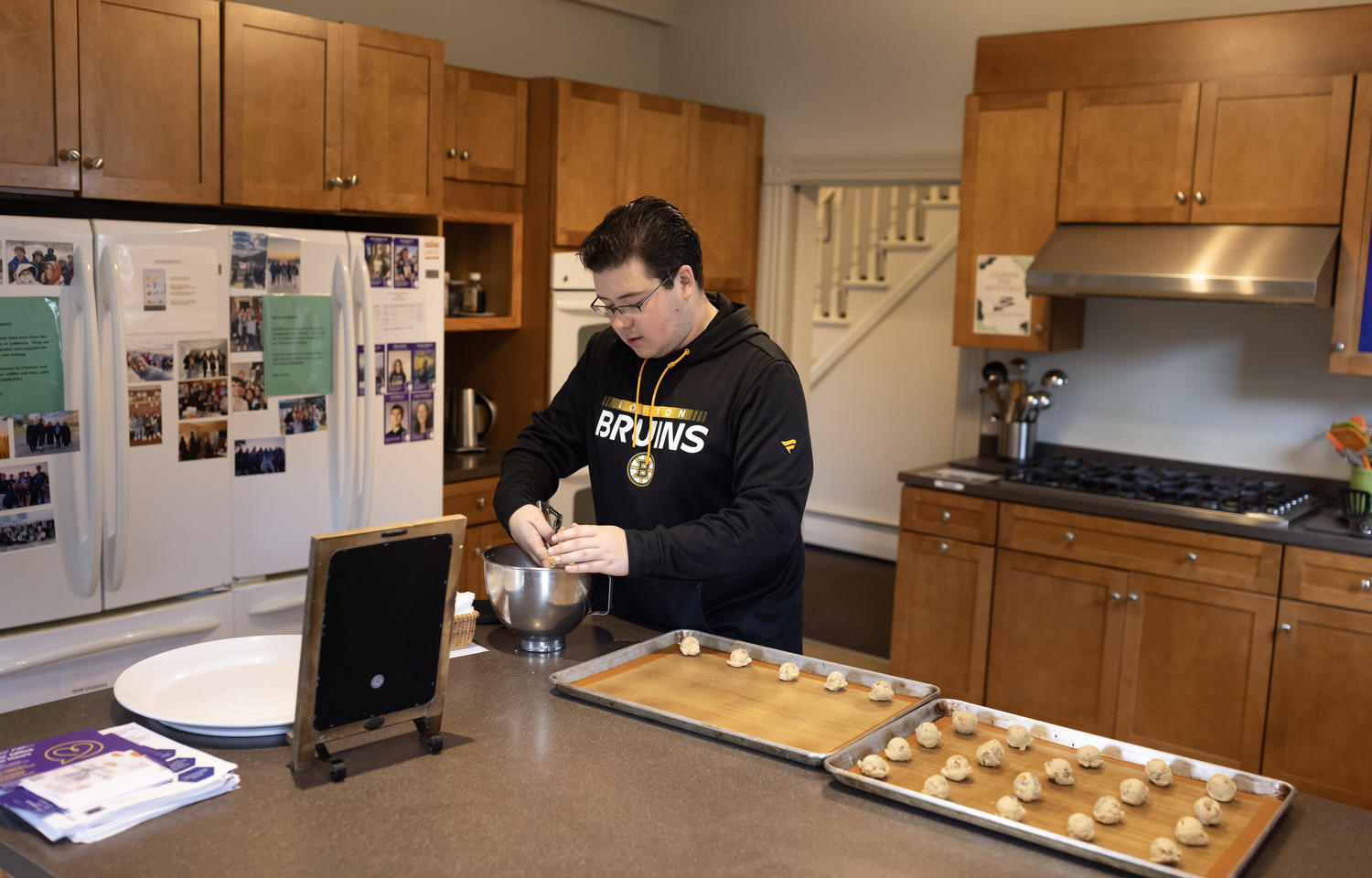 Man scoops cookie dough onto baking sheet