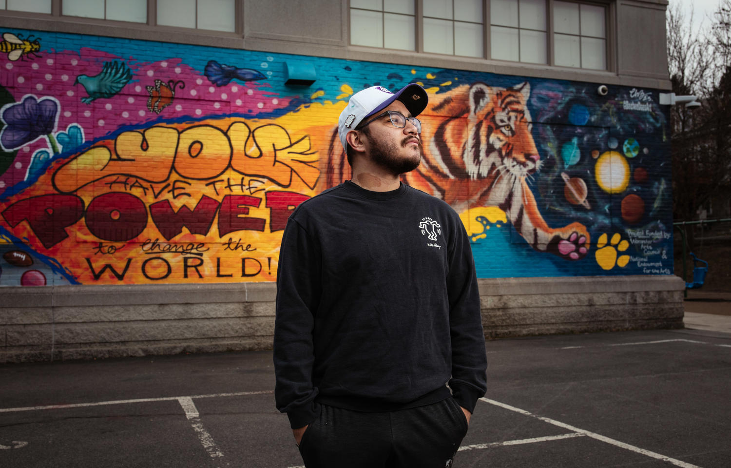 Man in hat stands in front of mural
