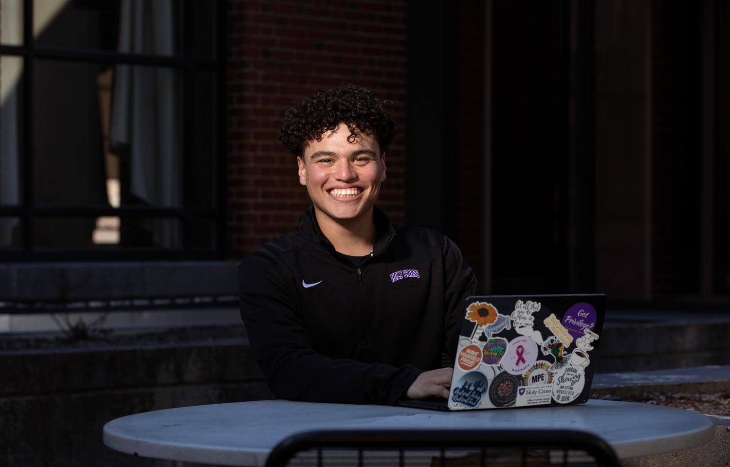 Young Hispanic male student sitting at a table with a laptop.