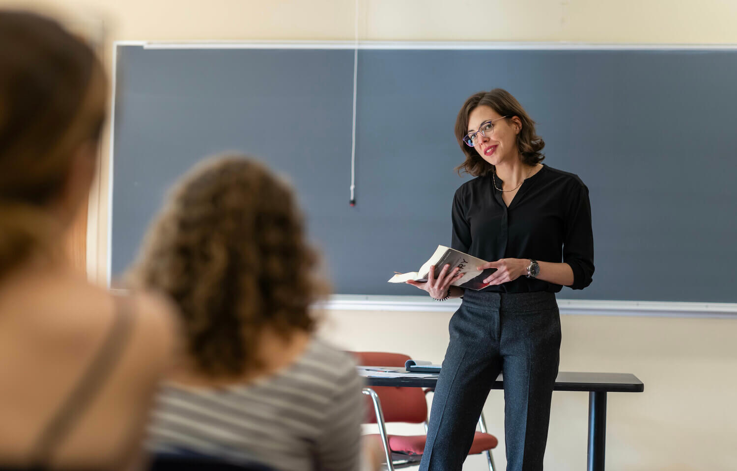woman in front of a blackboard with poetry book