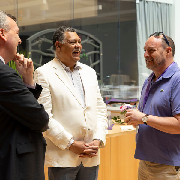 three men talking at a reception
