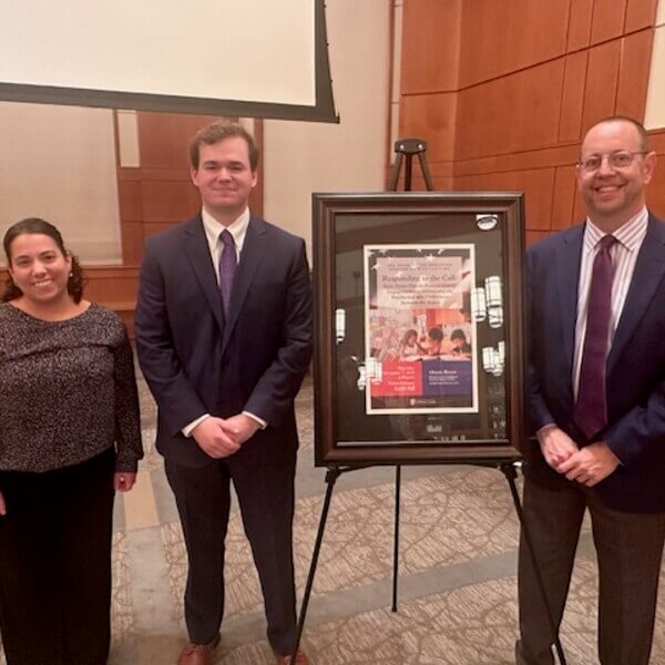 Three people standing in front of an easel.