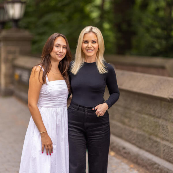 Two women stand together near park in New York City.