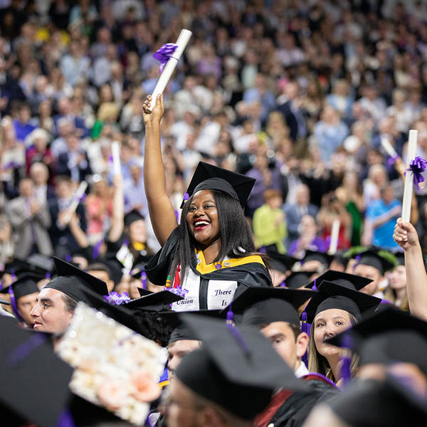 A graduating student waves her diploma at the 2019 Holy Cross graduation.