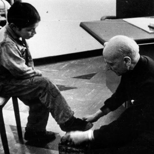 Man kneeling at the feet of a seated child.