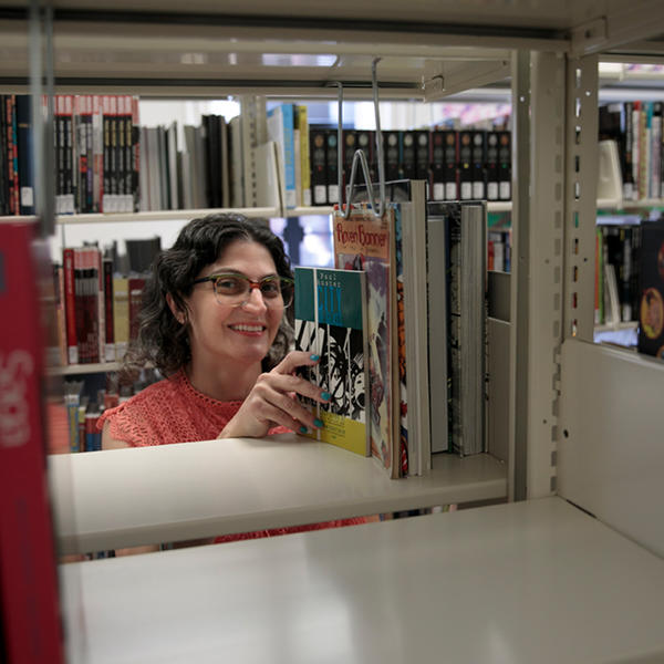 Woman reaching for a book on a library shelf