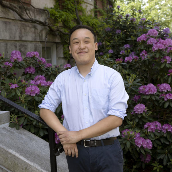 Dennis Liu, a student at the College of the Holy Cross, poses in front of flowers.