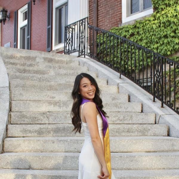 Isabelle Uong, a student at the College of the Holy Cross, poses at the base of granite stairs in a white dress.