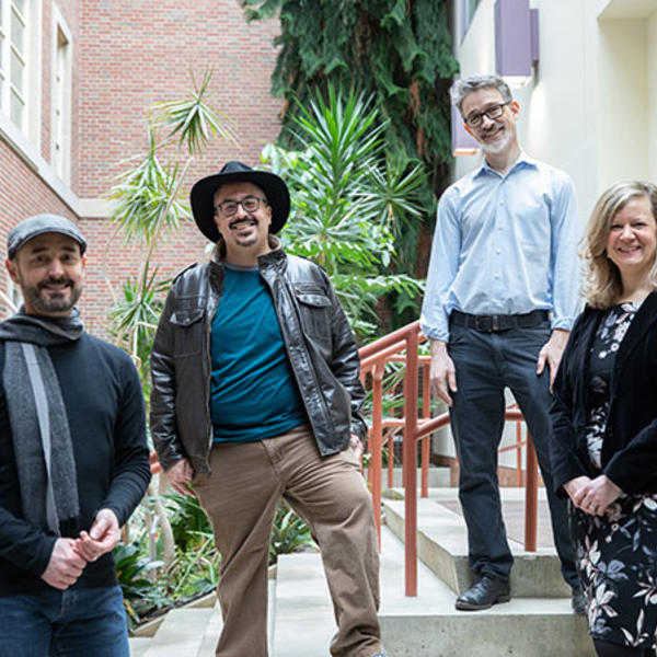 Ellis Jones, Jorge Santos, Jeremy Jones and Karen V Guth standing on stairs in an atrium filled with plants