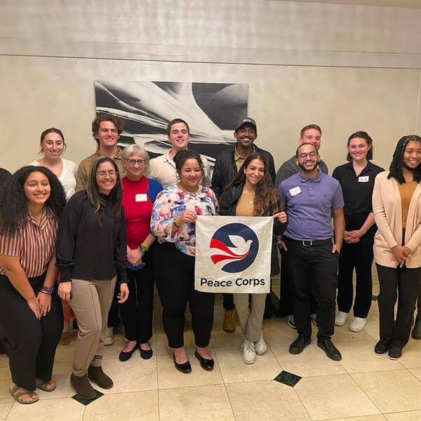 Peace Corps volunteers pose for a group photo inside a conference room.