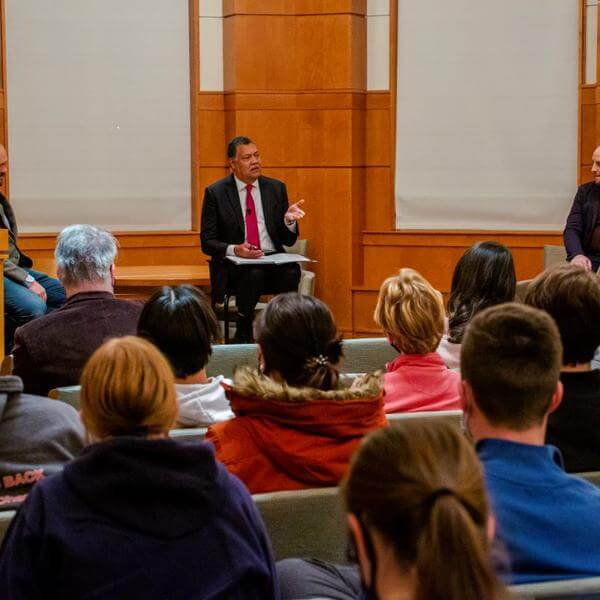 Ross Douthat of the New York Times, President Vincent Rougeau, and Matthew Sitman, associate editor of Commonweal Magazine, sit in front of a crowd in Rehm Library