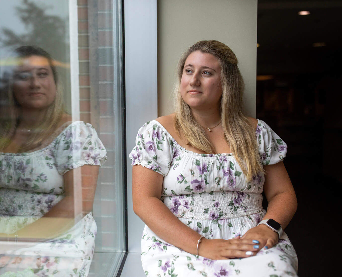 Woman sits on windowsill and looks out window