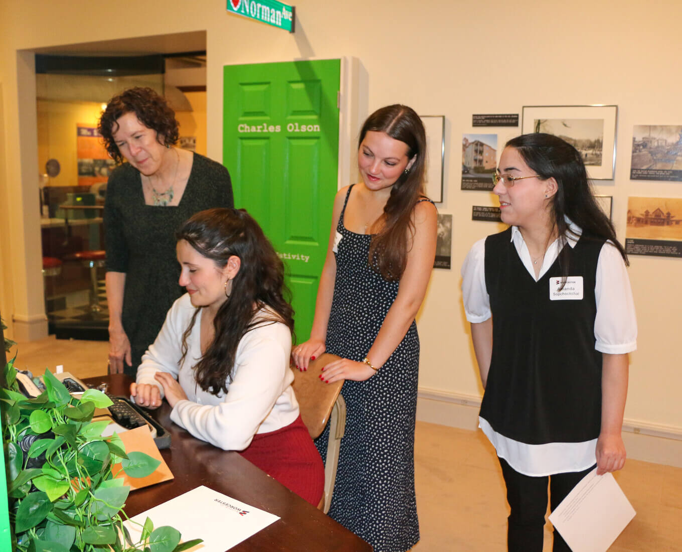 Women gathered around a woman typing