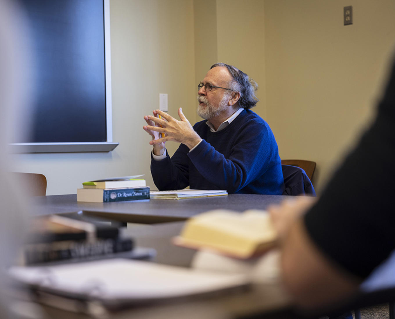 Professor John Little sits in a classroom