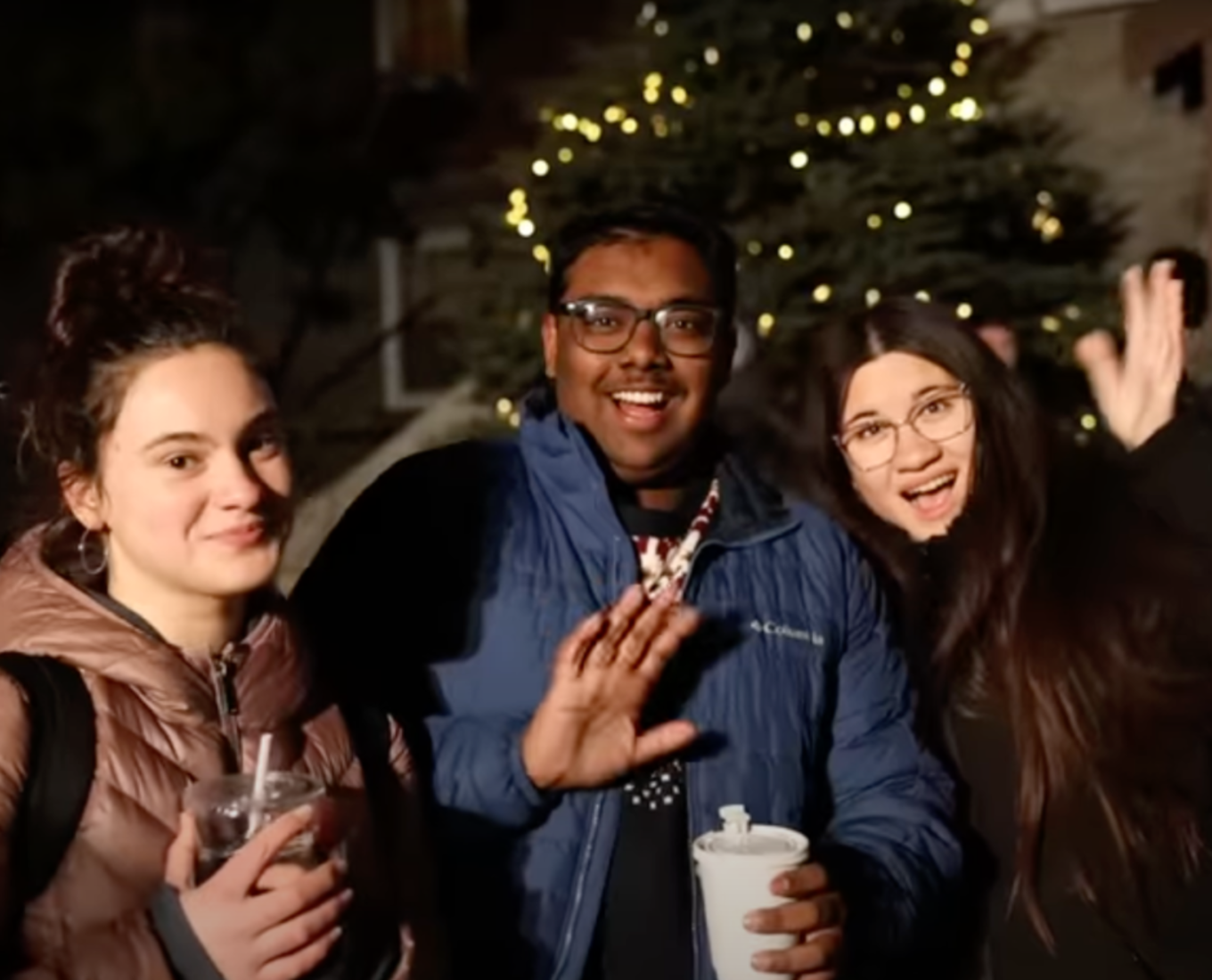 Students waving to the camera outside in the winter.